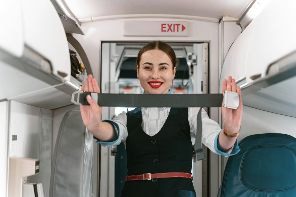 Beautiful flight attendant demonstrates flight safety instruction by using seat belt