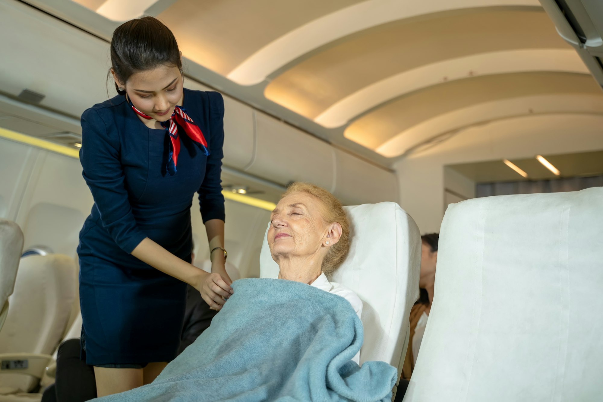 Flight attendant fastening blanket to passenger in planes,Airline transportation and tourism.