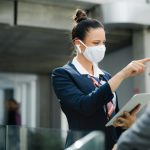 Flight attendant talking to businessman on airport, wearing face mask